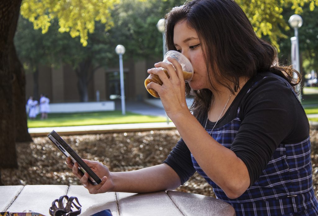 Photo Illustration: Student drinks coffee as she watches something online.