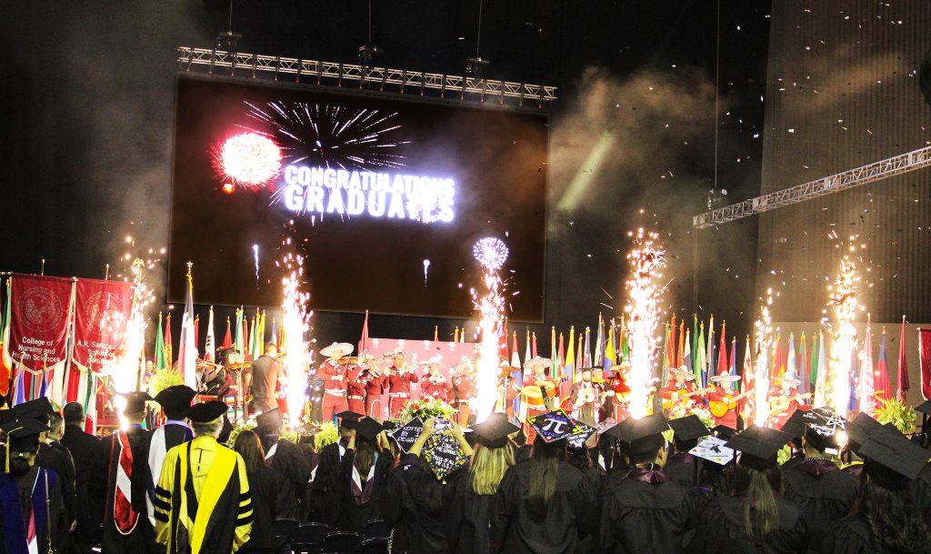 pyrotechnics and confetti explode to signify the end of commencement exercises as the Mariachi Internacional members perform on stage