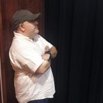 Theater professor stands behind the curtain on stage at TAMIU