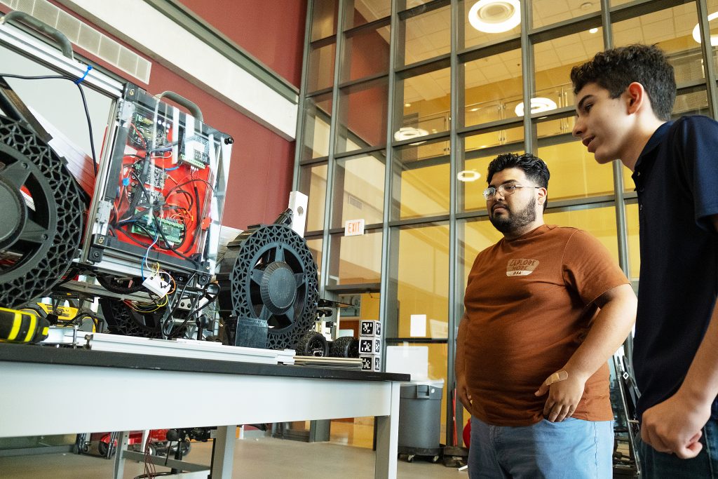 STEM students look over an electronics and mechanical project.