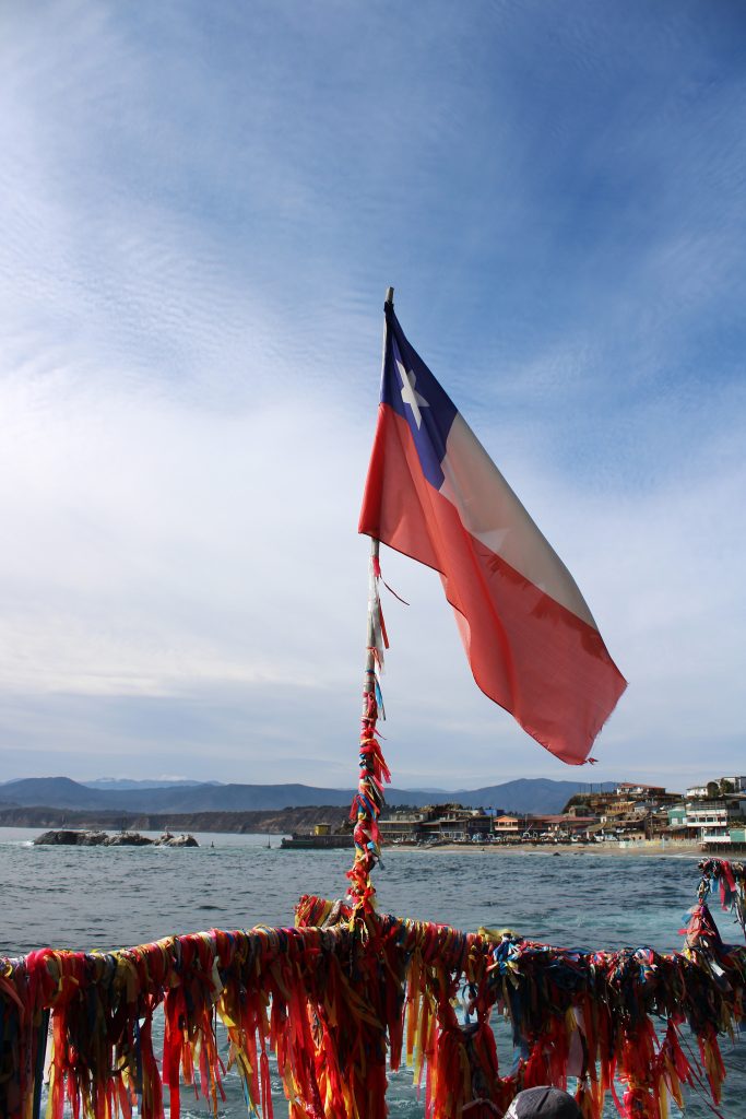 The Chilean flag flies on a bridge leading to a small island at Horcon Beach.