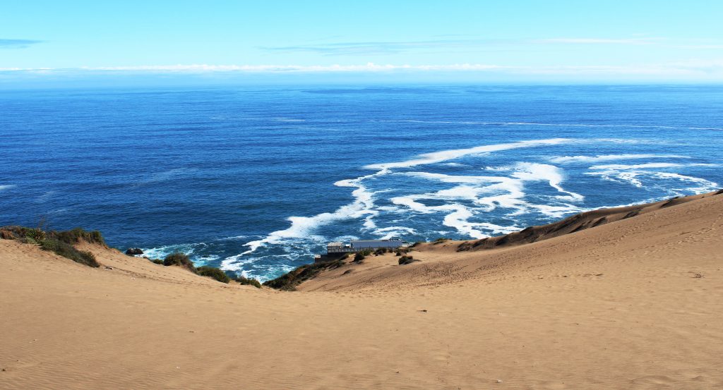 A large sandy hill with the Concon Dunes that leads down to the oceanfront in Chile.