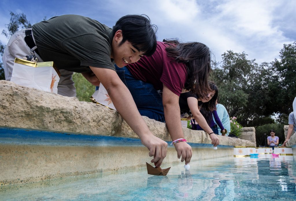 Students put paper boats into the campus fountain.