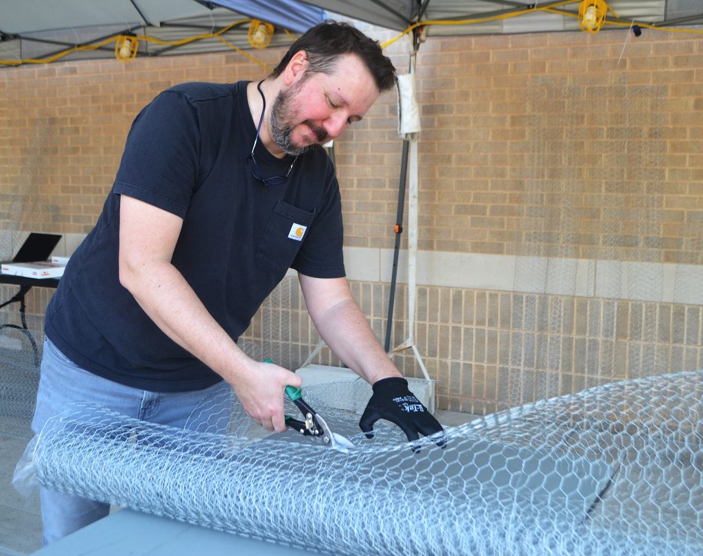 Assistant Professor of art Jesse Shaw cuts metal framework for Rhizome.