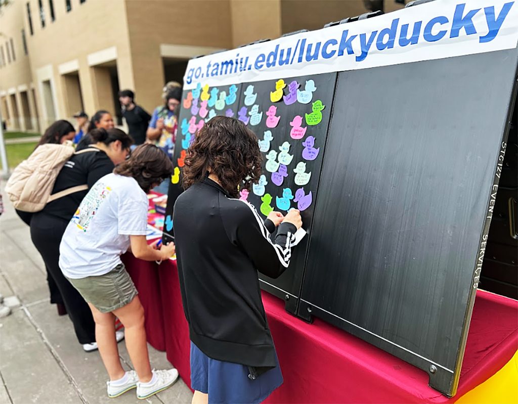Students post duck-shaped messages on a board.
