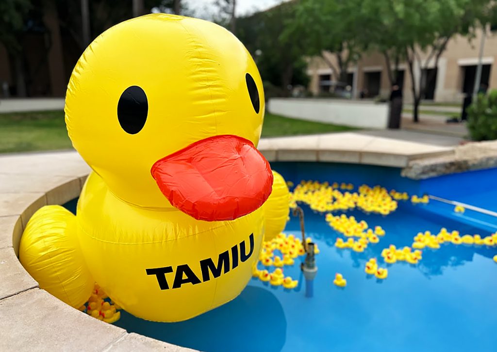 A giant inflatable rubber duckie and a bunch of smaller rubber duckies in a fountain.