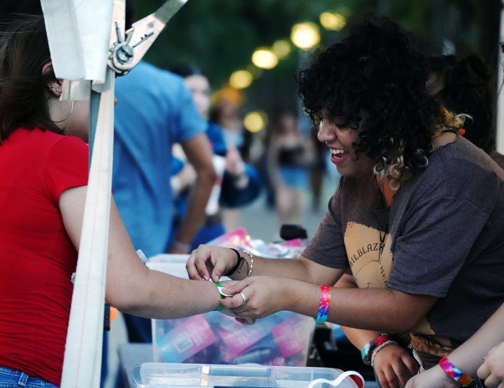 Student worker hands something to a participant at CABchella event.