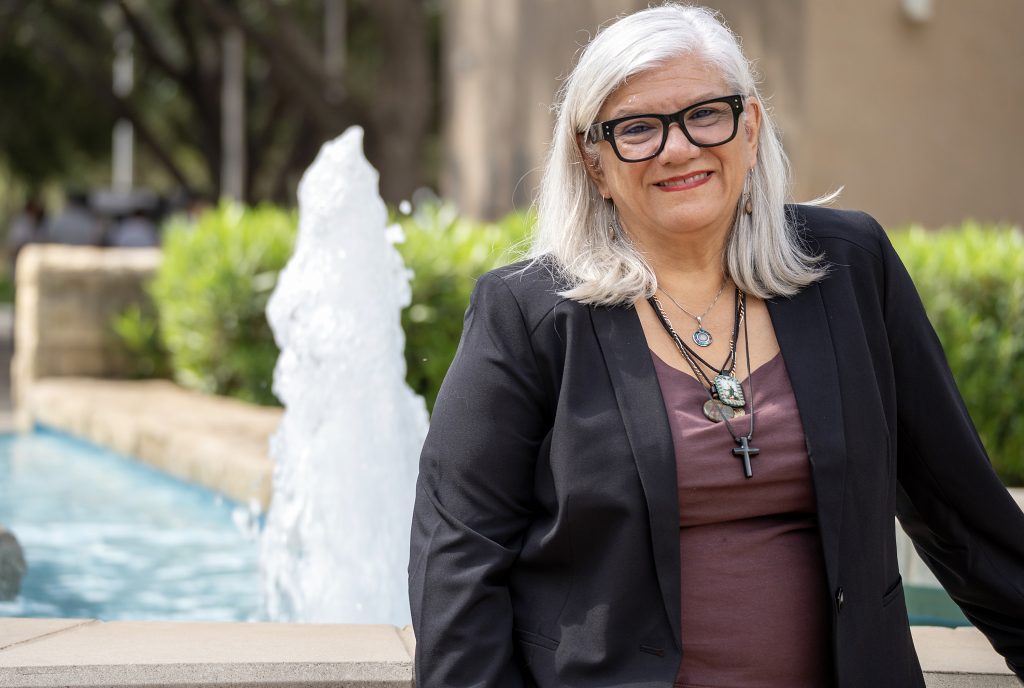 New dean of nursing poses for a photo by a fountain on campus.