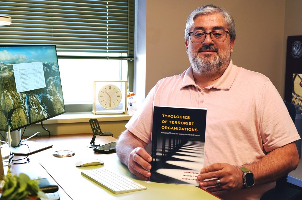 Professor holds book and poses for a portrait.