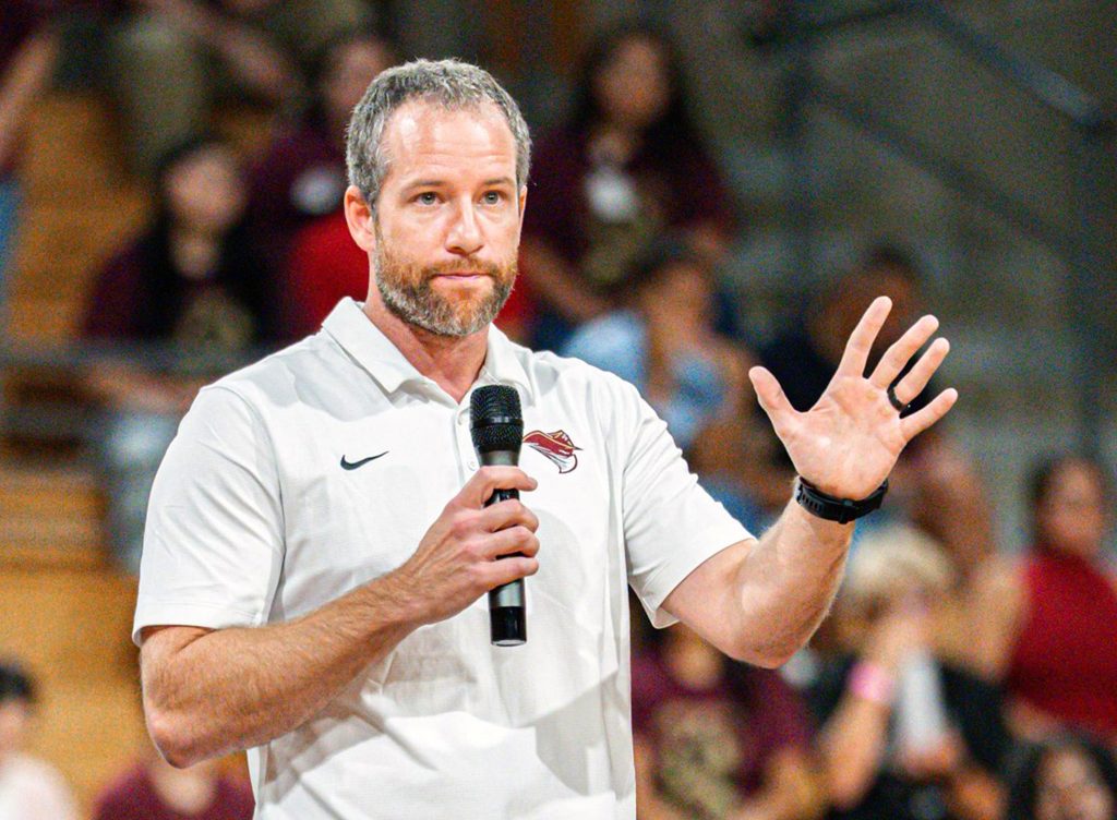 New coach speaks during a basketball game event.