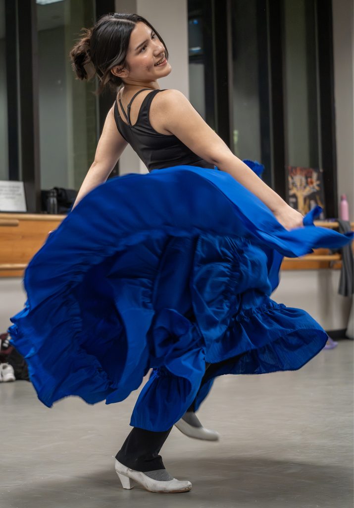 A dancer in a blue folklorico dress dances.
