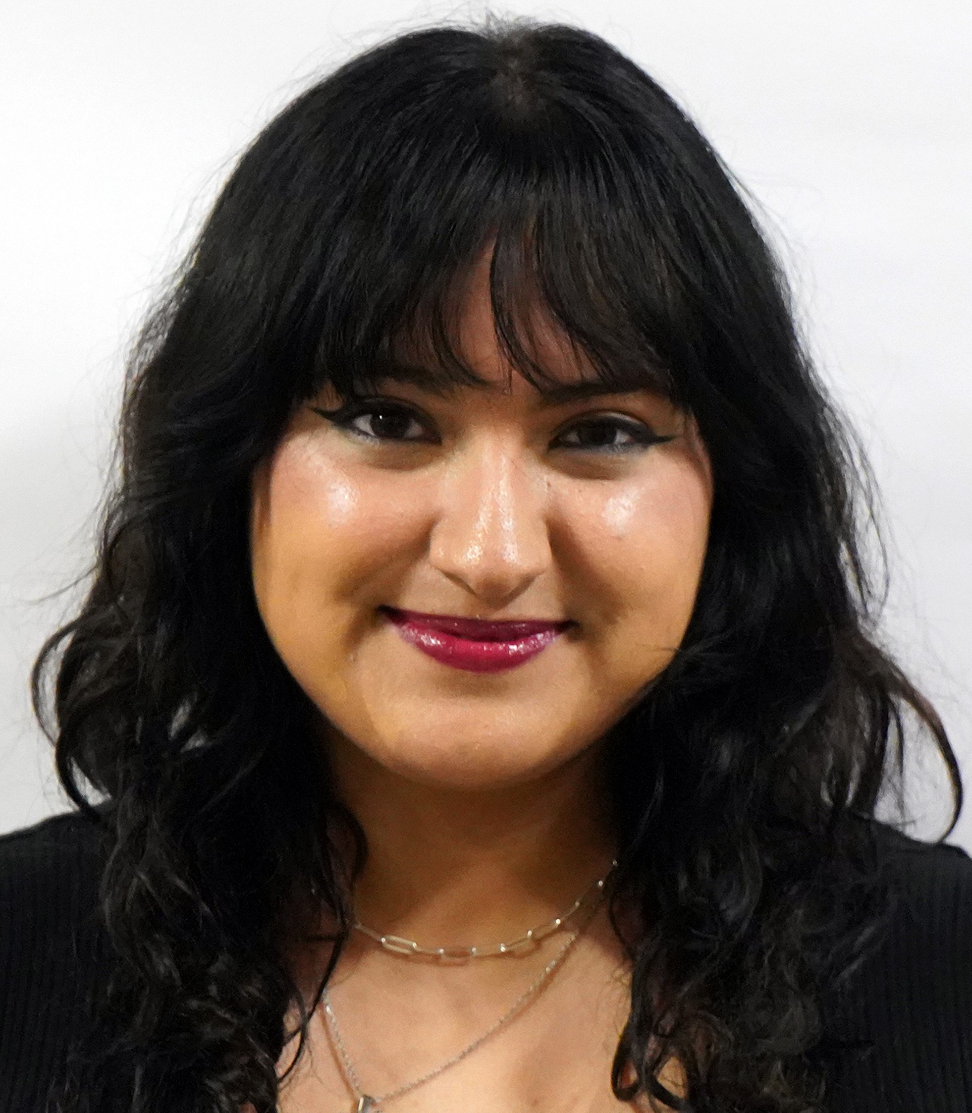 Portrait of dark haired woman with a dark top and a necklace