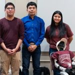 Four engineering students pose for a group photo with a robot.