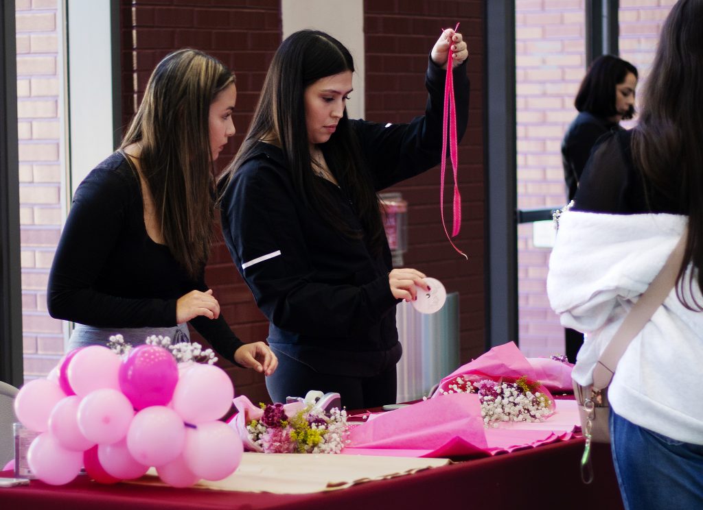 Two female students put together bouquets of flowers.