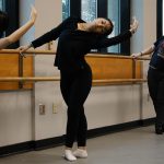 three contemporary dancers practice their form in a classroom