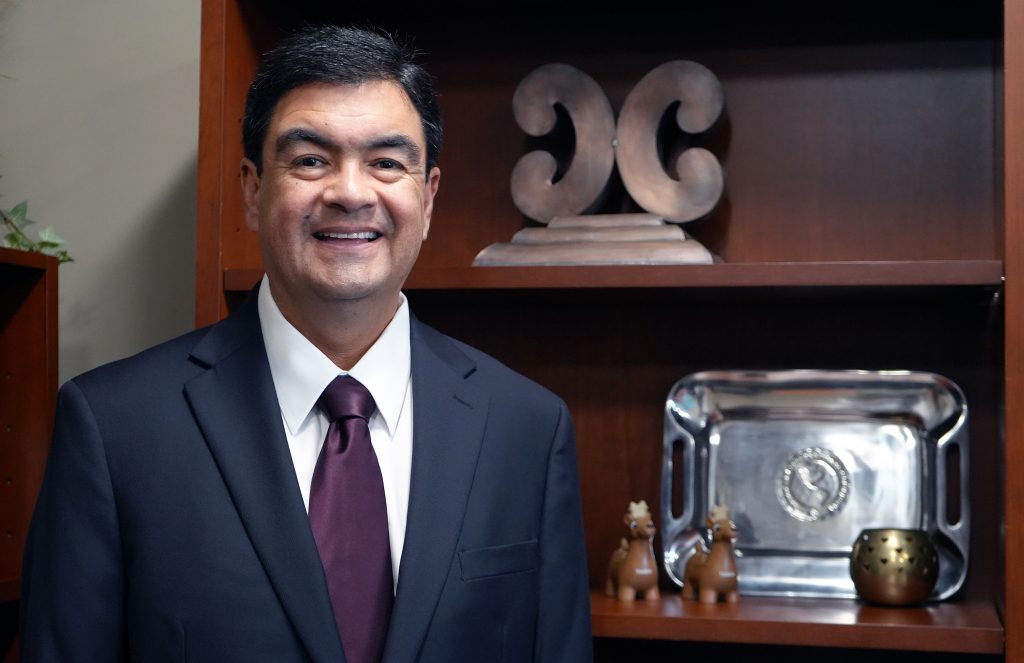 A person poses for a photo next to office decorations.