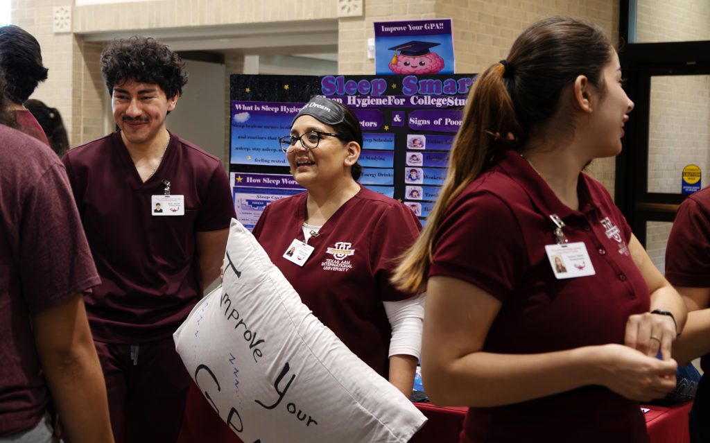 Nursing students at the health fair. One holds a pillow.