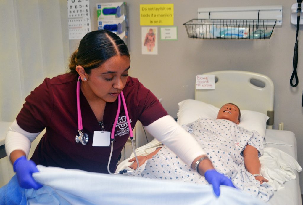 Nursing student works on an artificial patient (dummy) in the simulation lab.