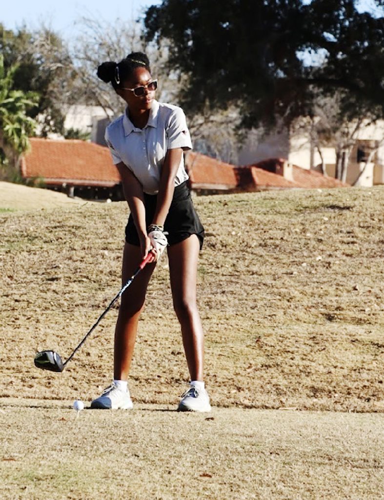 A golfer stands with golf club in hand ready to hit the ball off the tee.
