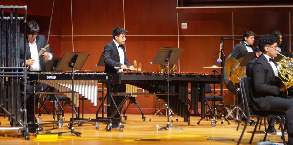 students and faculty perform with musical instruments during a recital.