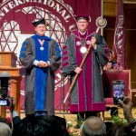 TAMIU President holds the official University mace on stage.
