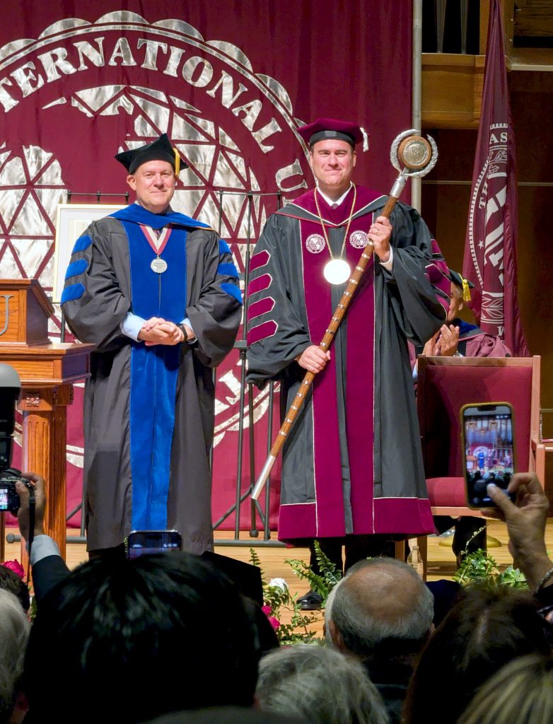 TAMIU President holds the official University mace on stage.